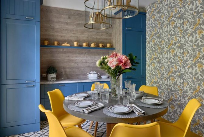 синие кухонные шкафчики и желтые стулья за круглым столом